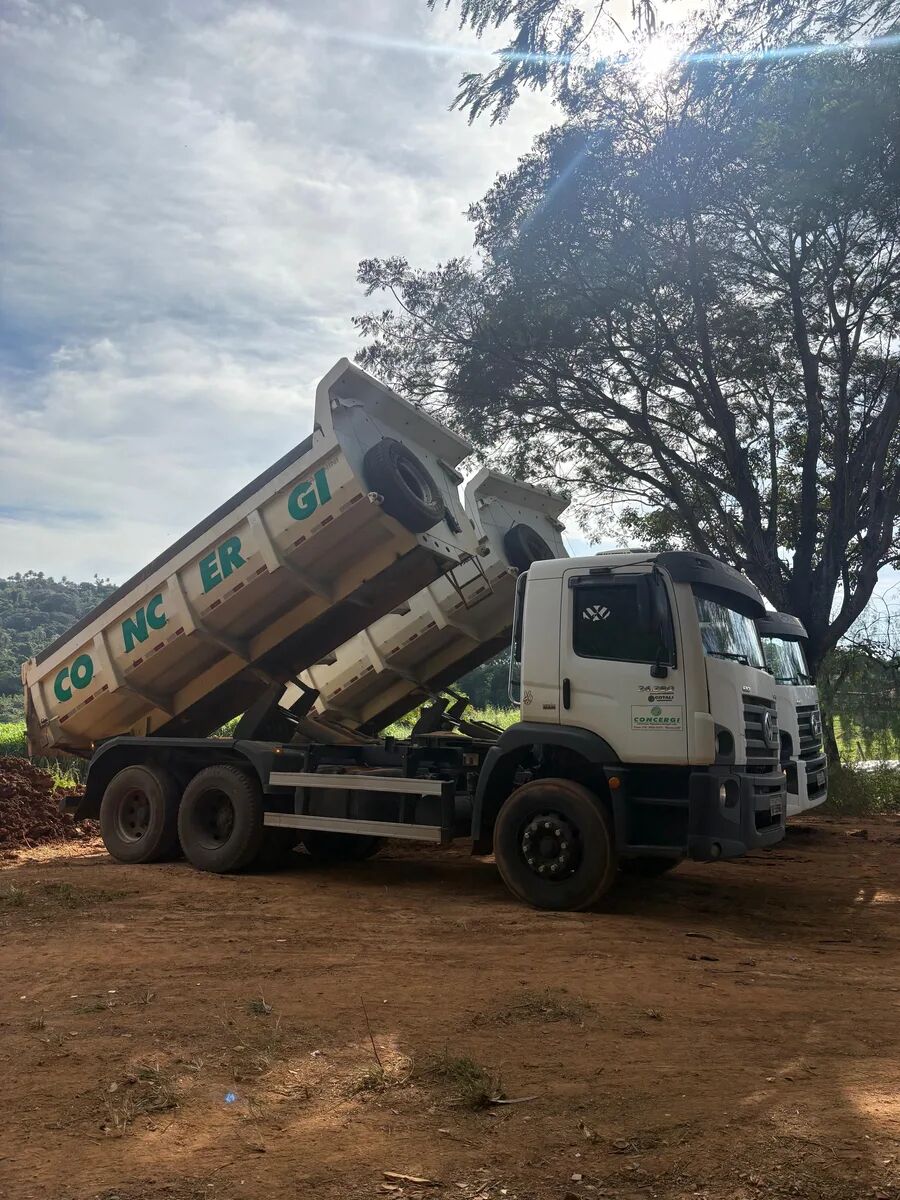 caminhões basculantes CONCERGI descarregando com a caçamba levantada — frota disponível para locação