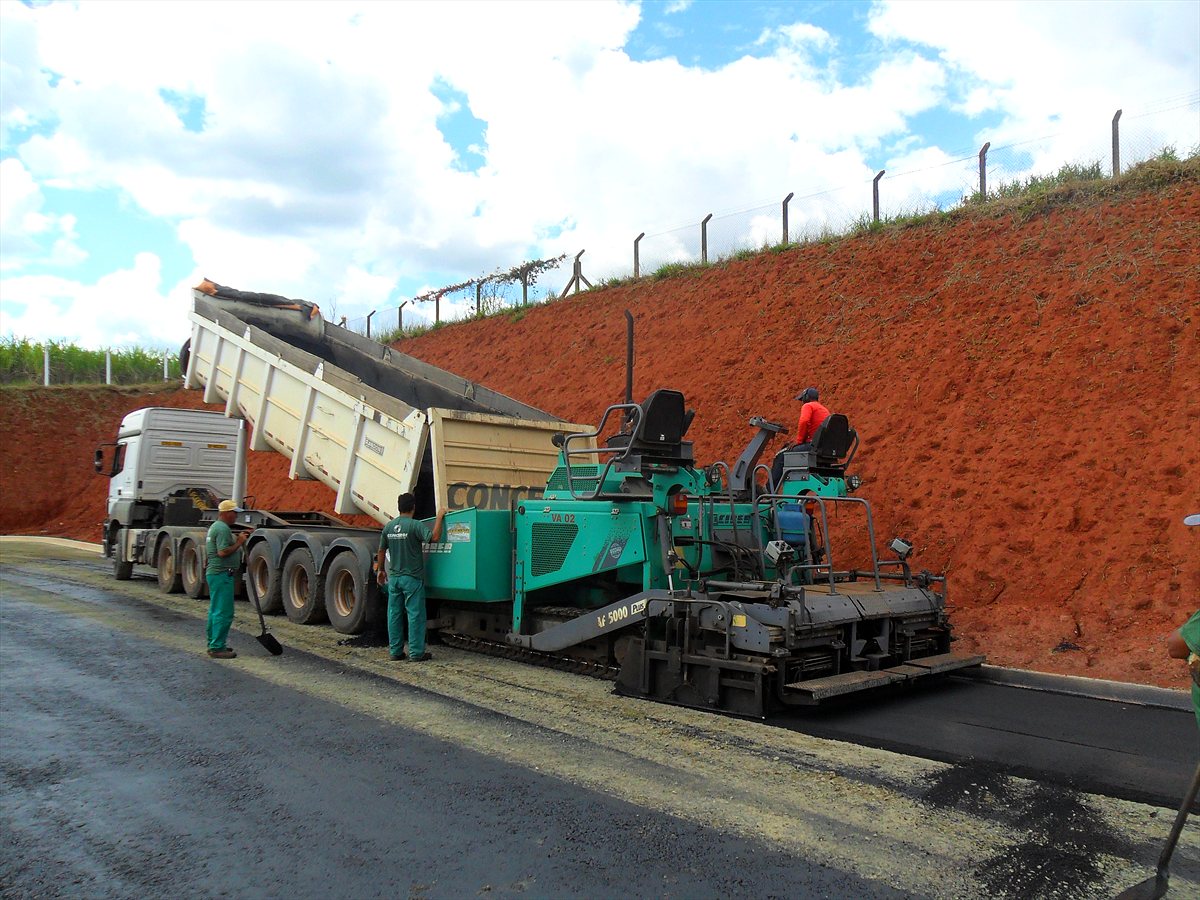 Vibroacabadora aplicando CBUQ em rodovia, alimentada por caminhão basculante da frota CONCERGI