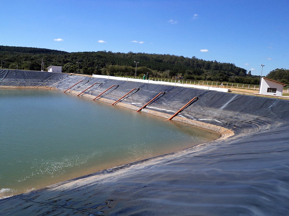 Reservatório concluído e cheio, com geomembrana PEAD e tubulações de recalque instaladas