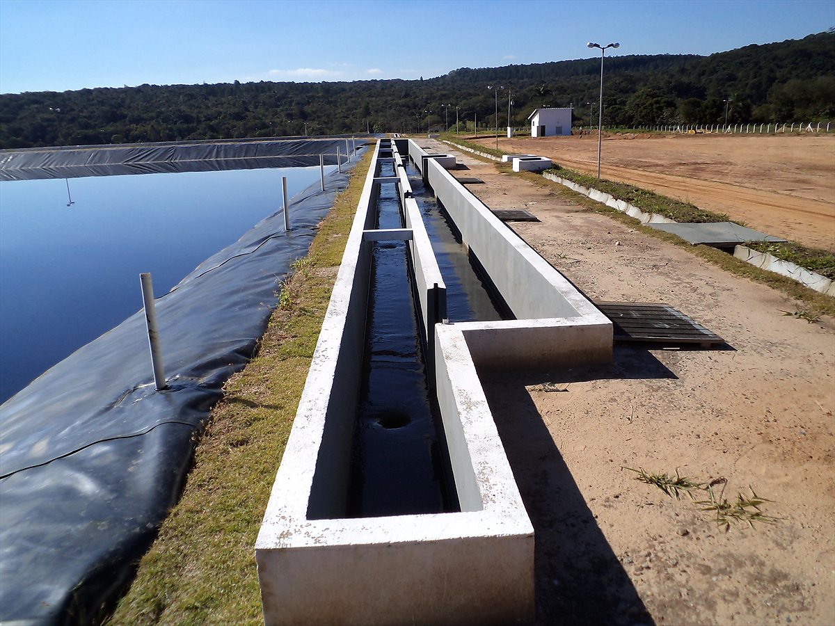Canal extravasor de concreto ao lado de reservatório impermeabilizado com geomembrana PEAD