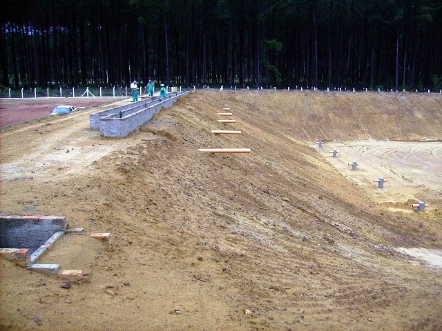 Escavação e estruturas de concreto de lagoa de tratamento em construção, antes da impermeabilização