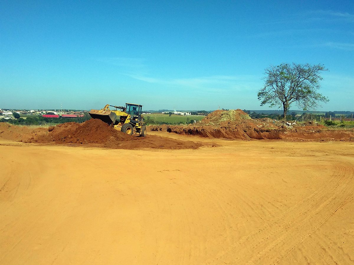Pá-carregadeira movimentando solo em terreno preparado para loteamento